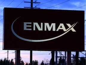 Power lines rise behind an Enmax sign at the company's head office in Calgary.