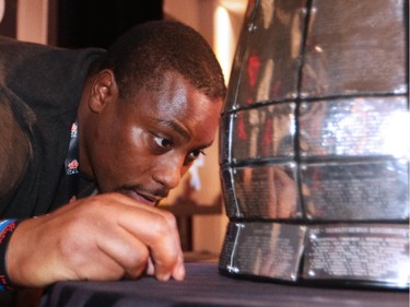 Nik Lewis takes a close-up look at the Grey Cup during the Calgary Stampeders - CFL West Champions media lunch at the Hyatt Regency Hotel in Vancouver on Thursday November 27, 2014.