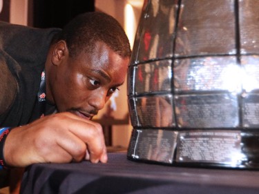 Nik Lewis takes a close-up look at the Grey Cup during the Calgary Stampeders - CFL West Champions media lunch at the Hyatt Regency Hotel in Vancouver on Thursday, November 27, 2014.