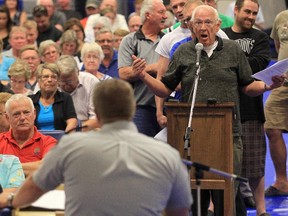 High River resident Don Watson poses a question to RCMP Staff Sgt. Ian Shardlow during a town hall meeting in September 2013 addressing the actions of the RCMP during the June flood.