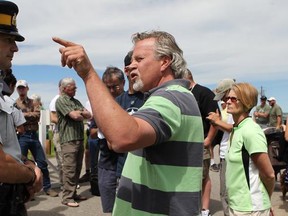 Staff Sgt. Kevin Morton tries to help Jeff Langford, green shirt middle, with Ian Scheelar, left and Greg Kvisle come up with a plan to help him get some answers. Evacuees confronted the RCMP on the northwest corner of town in a bid to enter the Town of High River on Thursday, June 27th 2013, one week after the Highwood River flooded leaving the whole town empty.  The protest stopped after and hour and a half but plans are to make it bigger on Friday.