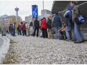 Homeless people line up outside the Calgary Drop In Centre in October 2014 to catch a bus to another shelter.