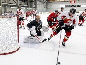 Calgary Flames goalie Joey MacDonald, centre, follows the puck as Tyler Wotherspoon, skates past with it during training camp in Calgary, Thursday, Sept. 12, 2013.