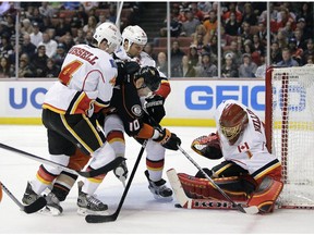 Anaheim Ducks' Corey Perry(10) is defended by Calgary Flames' Kris Russell(4) and Dennis Wideman(6) as he tries to score against goalie Jonas Hiller (1) during the second period of an NHL hockey game Tuesday, Nov. 25, 2014, in Anaheim, Calif.
