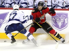 Calgary Flames centre Josh Jooris and Tampa Bay Lightning left winger Jonathan Drouin both overskated the puck as they fought for possession during second period NHL action at the Scotiabank Saddledome on October 21, 2014.