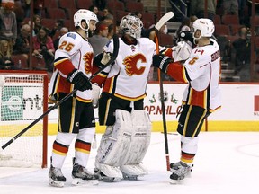 Calgary Flames winger Brandon Bollig, left, looks a little worse for wear after taking a puck in the nose prior to the finish of Saturday's game against Arizona when he joined Mark Giordano, right, in congratulating goalie Karri Ramo on a 3-0 shutout win.