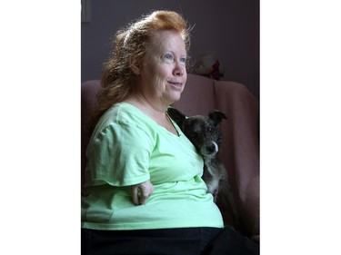 Marie Olney, born with born with disabilities from the drug thalidomide, sits with her dog Lennonx November 26.