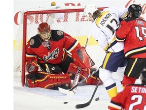 Ladislav Smid of the Calgary Flames ties up former Flame Olli Jokinen as the puck bounces in front of goalie Jonas Hiller during the second period at the Saddledome on Friday.