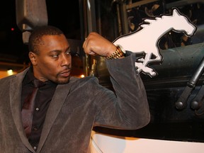 Calgary Stampeders veteran Nik Lewis flexes some muscle just prior to boarding the bus in the parking lot of McMahon Stadium Tuesday night as they prepare to depart to the airport for Vancouver to play in Sunday's Grey Cup against Hamilton. (David Moll/Calgary Herald)