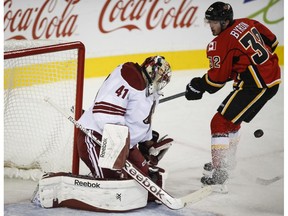 Arizona Coyotes goalie Mike Smith, left, deflects a shot from Calgary Flames Paul Byron during first period NHL hockey action at the Saddledome Nov. 13, 2014.