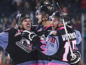 Kenton Helgesen #3 (L) of the Calgary Hitmen celebrates his goal against the Moose Jaw Warriors along with his teammates Keegan Kanzig #5 (C), and Jake Virtanen #18 (R) during a WHL game at Scotiabank Saddledome on November 21, 2014.