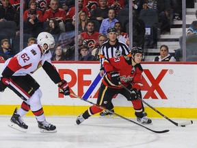 Johnny Gaudreau #13 of the Calgary Flames skates with the puck past Eric Gryba #62 of the Ottawa Senators during an NHL game at Scotiabank Saddledome on November 15, 2014 in Calgary, Alberta.