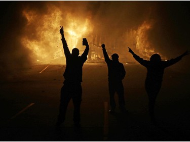 People watch as stores burn Tuesday, Nov. 25, 2014, in Ferguson, Mo. A grand jury has decided not to indict Ferguson police officer Darren Wilson in the death of Michael Brown, the unarmed, black 18-year-old whose fatal shooting sparked sometimes violent protests.