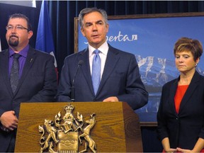 Alberta Premier Jim Prentice (centre) announces Nov.24, 2014, at the legislature in Edmonton that opposition Wildrose members Ian Donovan, left, and Kerry Towle, right, have crossed the floor to join his Progressive Conservative caucus.