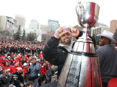 Stampeders kicker Sandro DeAngelis takes a picture of the Grey Cup sitting on the stage with Nik Lewis at a rally to celebrate the Stamps' 2008 Grey Cup win.