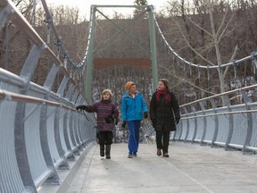 Diane Patterson, right, and her sons, Tazman, centre, and Kadin Abramowicz, left, walk across the newly reopened Sandy Beach Bridge, after being damaged in the 2013 floods, in Calgary on Sunday November 23, 2014.