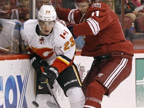 Calgary Flames' Sean Monahan (23) plays the puck off the boards as he is hit by Arizona Coyotes' Martin Hanzal during their Saturday night meeting.