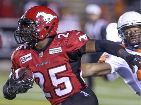 Stampeders Keon Raymond avoids a tackle from BC Lions Shawn Gore in Calgary, on September 27, 2014.