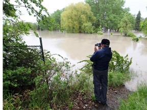 A man takes a video of the high water from the Bow River which flooded Bowness Park lagoon in June, 2013.