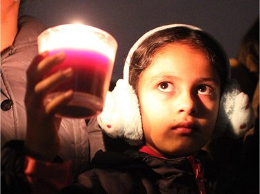 Divya Kaur, 7, looked at the candle she was holding as she joined her mom and dad along with a couple of hundred people as they gathered in an alley off Taracove Road NE near the site where a 17-year-old was abducted from and sexually assaulted last Friday night. The crowd gathered wearing glow sticks and carrying lights and candles to show their support for the victim and her family on November 20, 2014.