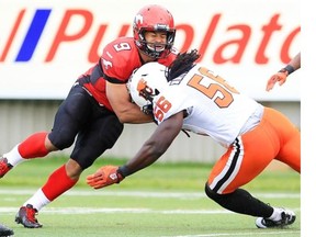 B.C.’s terrifying middle linebacker Solomon Elimimian crunches Stamps running back Jon Cornish during a game last season. With a win over Calgary on Friday, the Lions would clinch a trip to Edmonton for next weekend’s West semifinal.