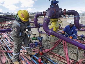 Workers tend to a well head at an Encana fracking gas well in western Colorado March 29, 2013.