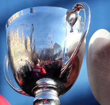 Calgary Stampeders Jon Cornish, right is reflected in the Grey Cup during the Grey Cup Champions rally at Calgary City Hall.