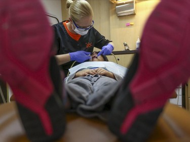 Christine Fairbairn, top, registered dental hygienist, performs a dental procedure on Marryam Dar, a Grade 3 student getting her teeth checked on The Alex Dental Health Bus in Calgary in November 2014.