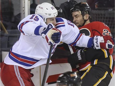 Calgary Flames Deryk Engelland takes a hit from New York Rangers Tanner Glass during third period action at the Scotiabank Saddledome in Calgary, on December 16, 2014.