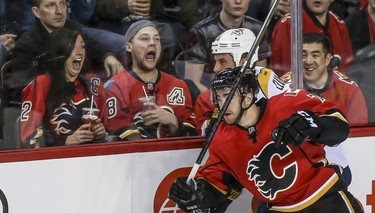 Two Calgary Flames fans are surprised as TJ Brodie, front, crushes Nashville Predator Craig Smith, into the boards at the Saddledome in Calgary on Friday, Jan. 24, 2014. The Flames won 5 to 4 after a shoot out.
