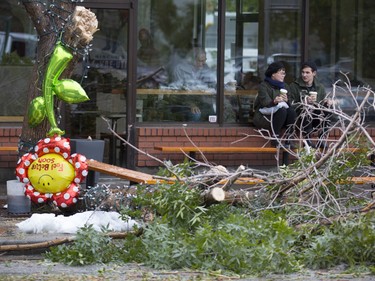 A "Feel Better Soon" balloon hangs from one of the trees fallen victim to the heavy, wet snow, in front of a coffee shop where Kelly Pleau, left, and Keaton Pridham sit in Calgary, on September 10, 2014.