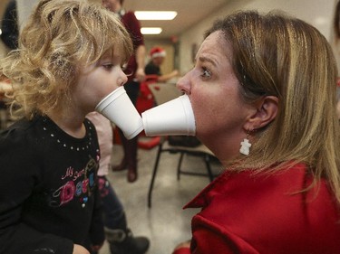 Health and Education Centre executive director, plays styrofoam cup lips with 3-year-old Sophie Delbridge during a Christmas party the Centre hosted for member families in Calgary, on December 19, 2014.