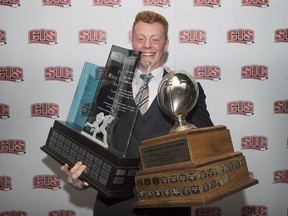Andrew Buckley, from the University of Calgary, holds up his Russ Jackson Centaur trophy, left, and Hec Crighton Trophy for most outstanding player of the year during the CIS football awards ceremony in Montreal last month.