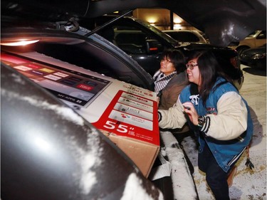 Lian Tolentino and her mom squeeze their new T.V. into their car at the Sunridge Best Buy just after 6:00 AM on Boxing Day. About 250 people some arriving as early as 3 AM waited outside the store for the 6:00 AM opening.