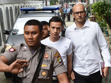 Canadian teacher Neil Bantleman and co-accused teaching assistant Ferdiand Tjiong are escorted by a policeman as they arrive at court in this file photo.