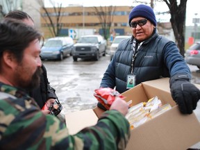 John Chief Moon, an outreach worker with the Canadian Mental Health Associations' Street Outreach and Stabilization (SOS) team, hands out food to bottle collectors outside the Uptown Bottle Depot in Calgary's Beltline area.
