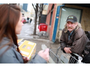 outreach worker with the Canadian Mental Health Associations' Street Outreach and Stabilization (SOS) team, talks with bottle collectors outside the Uptown Bottle Depot in Calgary's beltline. The team regularly hands out small food hampers and makes connections with those living on the street.  Up to seventy per cent of homeless individuals have a mental health concern. The SOS team helps to address the needs of these hard to reach individuals by connecting and working with them.