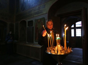 A women lights a candle at a Russian Orthodox church at Red Square in Moscow.