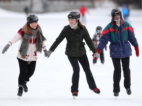 Calgary's Bailey Bjolin, left, joins sisters Vanessa Urschel, centre, and Sydney Urschel for a  skate around the reopened skating area on the Bowness Park lagoon on December 25, 2014. The Urschel sisters said it is their Christmas Day tradition to skate on Bowness lagoon, where they both learnt to skate when they were young.