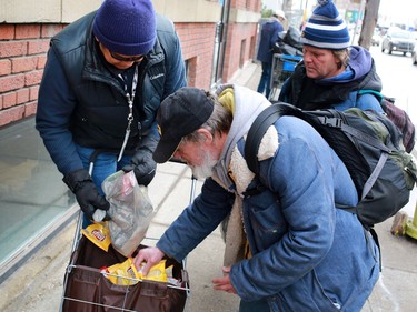 John Chief Moon, an outreach worker with the Canadian Mental Health Associations' Street Outreach and Stabilization (SOS) team, hands out food to bottle collectors in Calgary's beltline during a routine circuit on December 9, 2014.