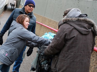 John Chief Moon and Tanya Richer with the SOS team, hand out food to a bottle collector in Calgary's beltline. The team regularly hands out small food hampers and makes connections with those living on the street.