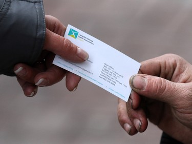 Tanya Richer, an outreach worker with the Canadian Mental Health Associations' Street Outreach and Stabilization (SOS) team, hands a card to a young man along Stephen Avenue Mall in downtown Calgary while making a routine circuit through the downtown area.