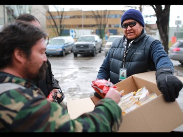John Chief Moon, a coordinator with the Canadian Mental Health Associations' Street Outreach and Stabilization (SOS) team, hands out food to bottle collectors outside the Uptown Bottle Depot in Calgary's beltline. The team regularly hands out small food hampers and makes connections with those living on the street.