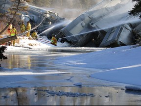 Banff firefighters spray water to keep dust down as CP crews deal with a 15 car train derailment in Banff at the rail bridge over 40 Mile Creek.