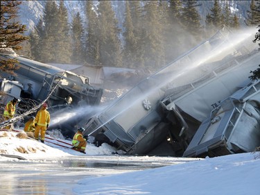 Banff firefighters spray water to keep dust down as CP crews deal with a 15 car train derailment in Banff at the rail bridge over 40 Mile Creek.