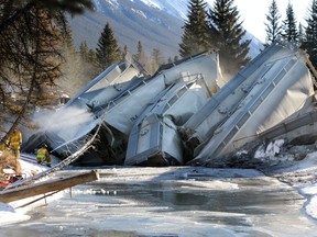 Banff firefighters spray water to keep dust down from spilled fly ash as CP crews deal with a 7 car train derailment in Banff at the rail bridge over 40 Mile Creek.