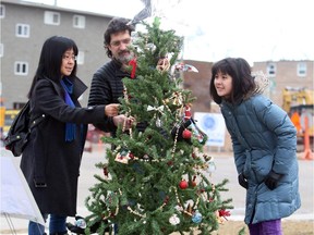 Tamara Lee, Danny Levinson and fourteen year old Katie Levinson check out the new ornaments on the community tree they put up in Sunnyside.