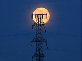 A full moon hangs in the sky over power lines in Calgary.