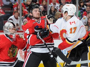 Tim Erixon of the Chicago Blackhawks and Lance Bouma of the Calgary Flames get physical in front of goalie Antti Raanta on Sunday. Erixon, a former Flames draft pick, was dealt to the Blackhawks on Sunday morning.