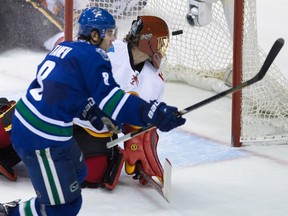 Vancouver's Chris Tanev, left, scores the winning goal against Calgary Flames' goalie Jonas Hiller during the overtime period of an NHL hockey game in Vancouver on Saturday.